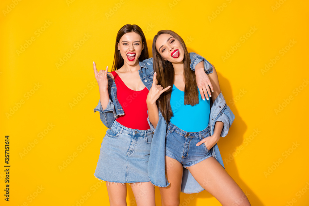 Portrait of crazy funny excited girls enjoy rock and roll pank weekend concert show horns symbol wear jeans tank-top isolated over bright shine color background Portrait of crazy funny excited girls enjoy rock and roll pank weekend concert show horns symbol wear jeans tank-top isolated over bright shine color background