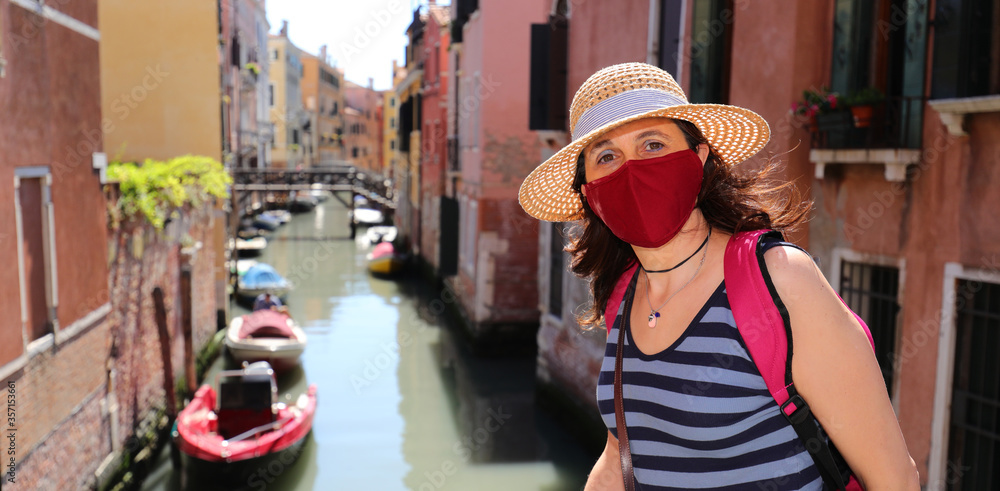 Woman with surgical mask and straw hat in Venice in Italy during