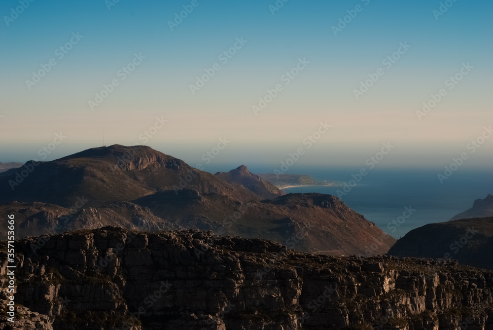 View from the top of Table Mountain, Cape Town in South Africa. Mountain in backround, bluea sky and ocean.
