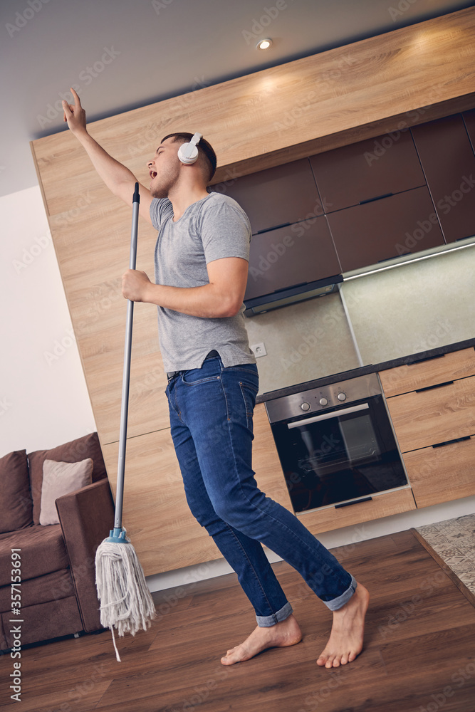 Young man singing while cleaning living room Young man singing while cleaning living room