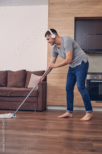 Young man cleaning parquet in living room