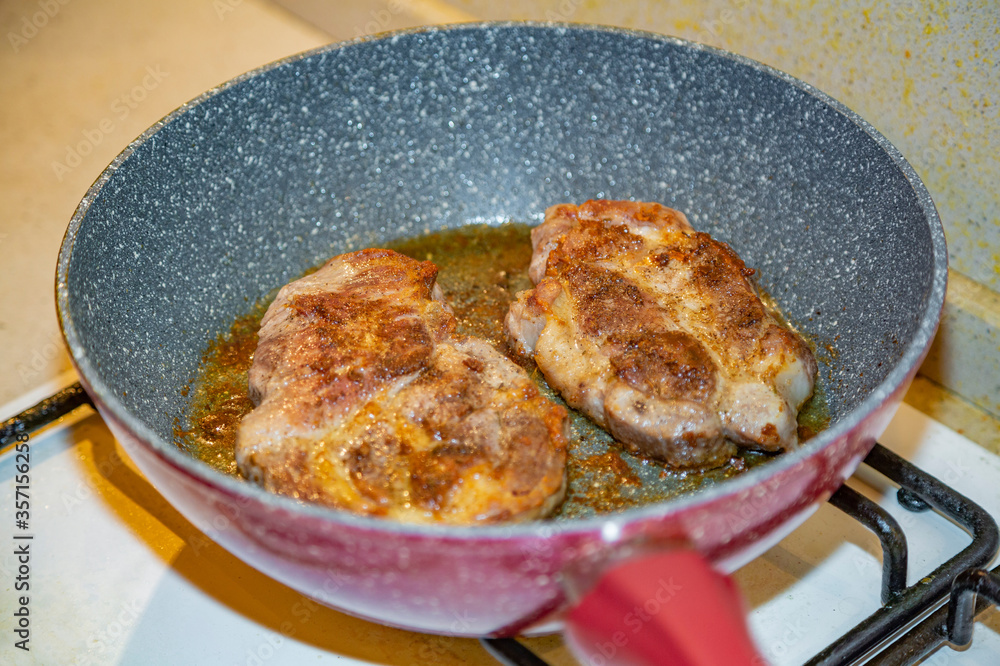 Juicy appetizing steaks from fat pork fried in a pan with olive oil Juicy appetizing steaks from fat pork fried in a pan with olive oil