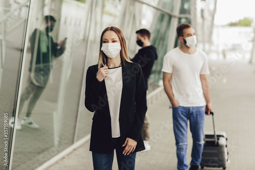 Figures of young people in protective masks near the airport. Safe travel during a pandemic. Airplane travel, quarantine and pandemic concept