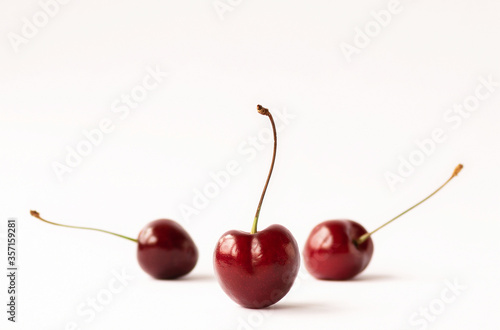 Three ripe cherries on a light background with space for text.