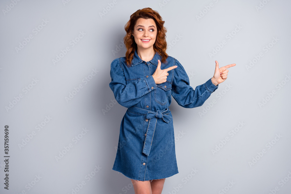 Photo of beautiful funny foxy lady directing fingers side empty space show novelty sale price product good mood wear casual blue denim short dress isolated grey color background Photo of beautiful funny foxy lady directing fingers side empty space show novelty sale price product good mood wear casual blue denim short dress isolated grey color background