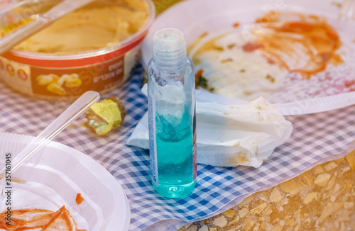 A bottle of gel for hand disinfection stands on a picnic table. Picnic in the nature.