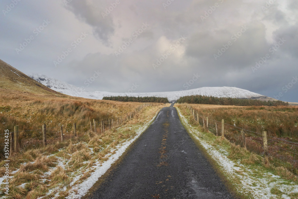 Road in a mountains, The Gleniff Horseshoe loop drive in county Sligo, Ireland, Mountains covered with snow, Winter season. Cloudy sky.