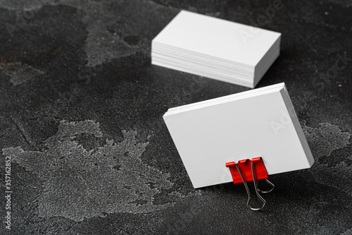 White businesscards united with a paper clip on a black rough background photo