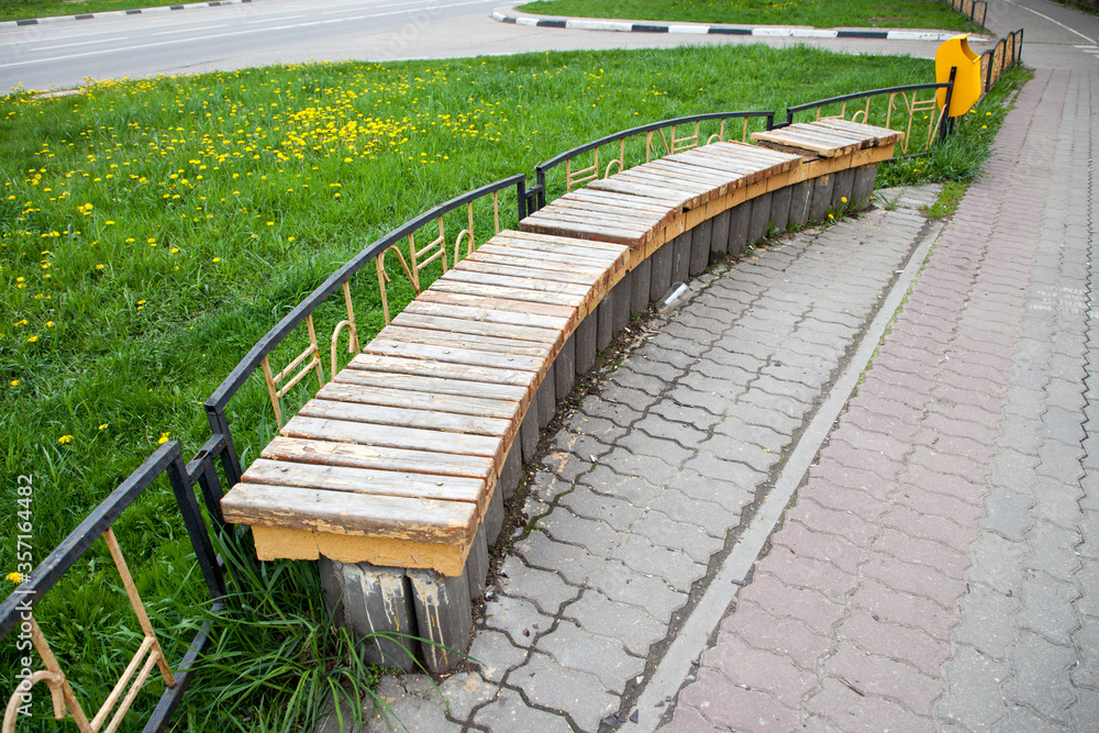 Wooden bench near a metal fence on a footpath Wooden bench near a metal fence on a footpath