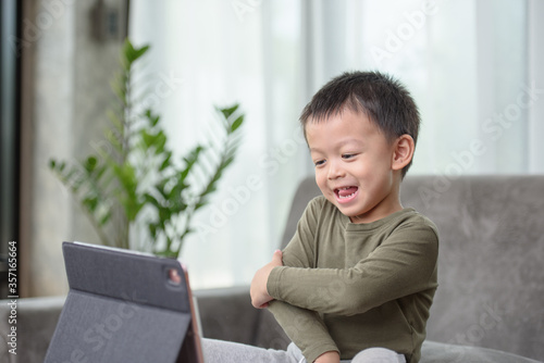 Asian boy with a cute face and good temper is looking and smiling at the camera in front of the tablet. While talking to friends via video call.