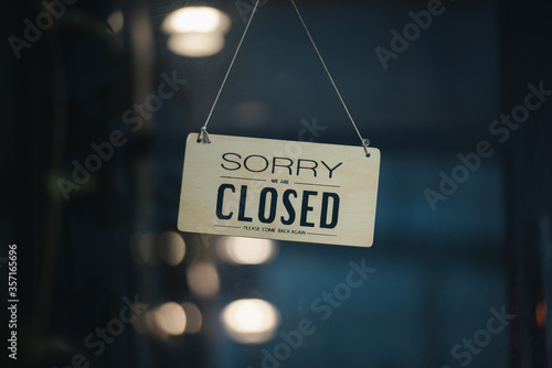 sorry we are closed sign hanging outside a restaurant, store, office or other. Closed sign in a shop showroom with reflections bokeh.