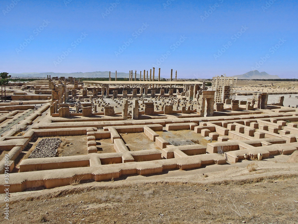 Side view on ruins of Palace of 100 Columns in Persepolis, ancient capital of Persian Empire. Columns on background is Apadana, heart of complex. Persepolis located near Shiraz, Iran