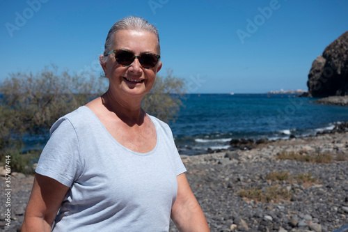 Cute and relaxed senior woman enjoying the outdoor at the sea - happy and smiling retired people with gray hair  horizon over water