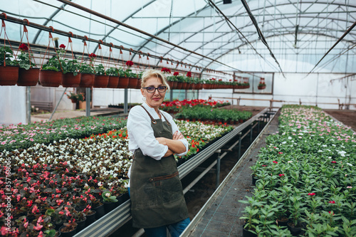 woman gardener in flower nursery standing crossed arms