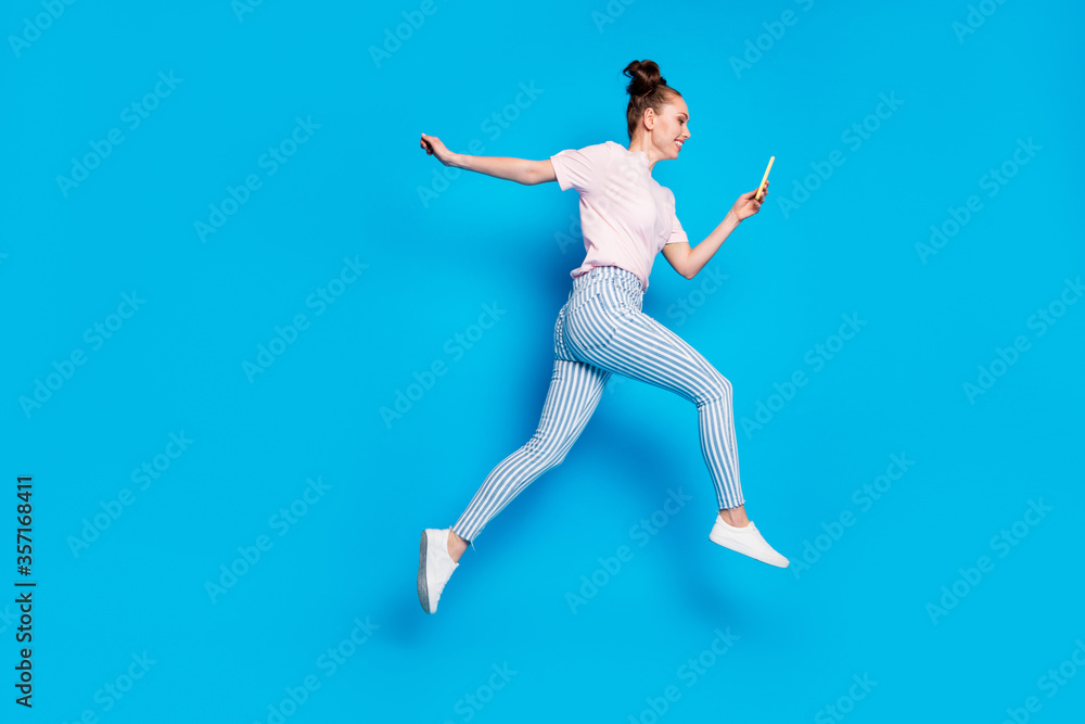 Full length body size view of her she nice attractive cheerful cheery girl blogger jumping going using cell app 5g blogging influencer isolated on bright vivid shine vibrant blue color background