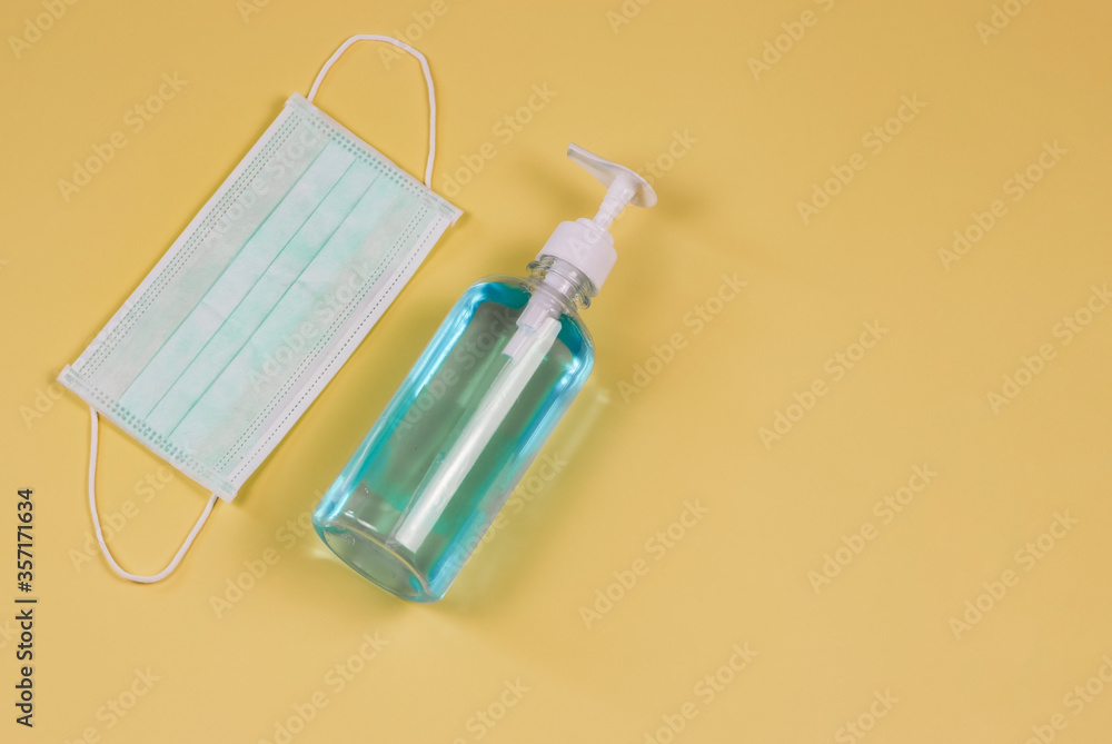 Coronavirus or COVID-19 prevention and new normal lifestyle concept. Top view of alcohol hand sanitizer gel and surgical face mask on yellow background Coronavirus or COVID-19 prevention and new normal lifestyle concept. Top view of alcohol hand sanitizer gel and surgical face mask on yellow background