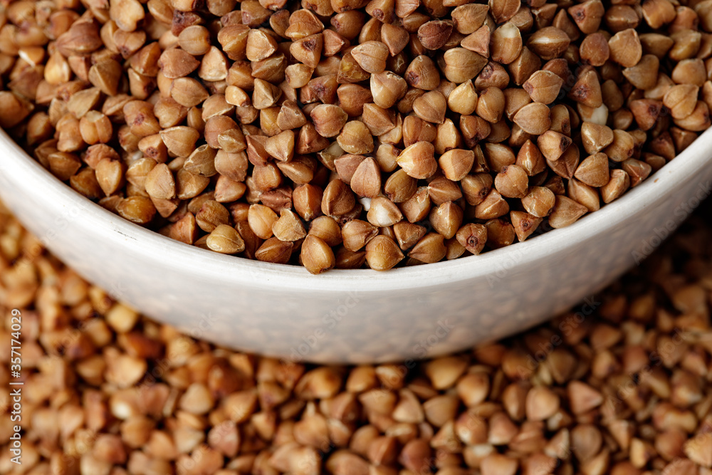 Bowl of raw uncooked buckwheat on wooden table Bowl of raw uncooked buckwheat on wooden table