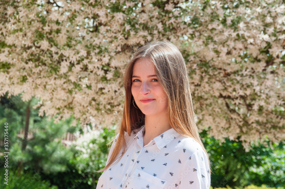 Sunny portrait of an incredibly beautiful girl on a summer day near a flowering tree Sunny portrait of an incredibly beautiful girl on a summer day near a flowering tree