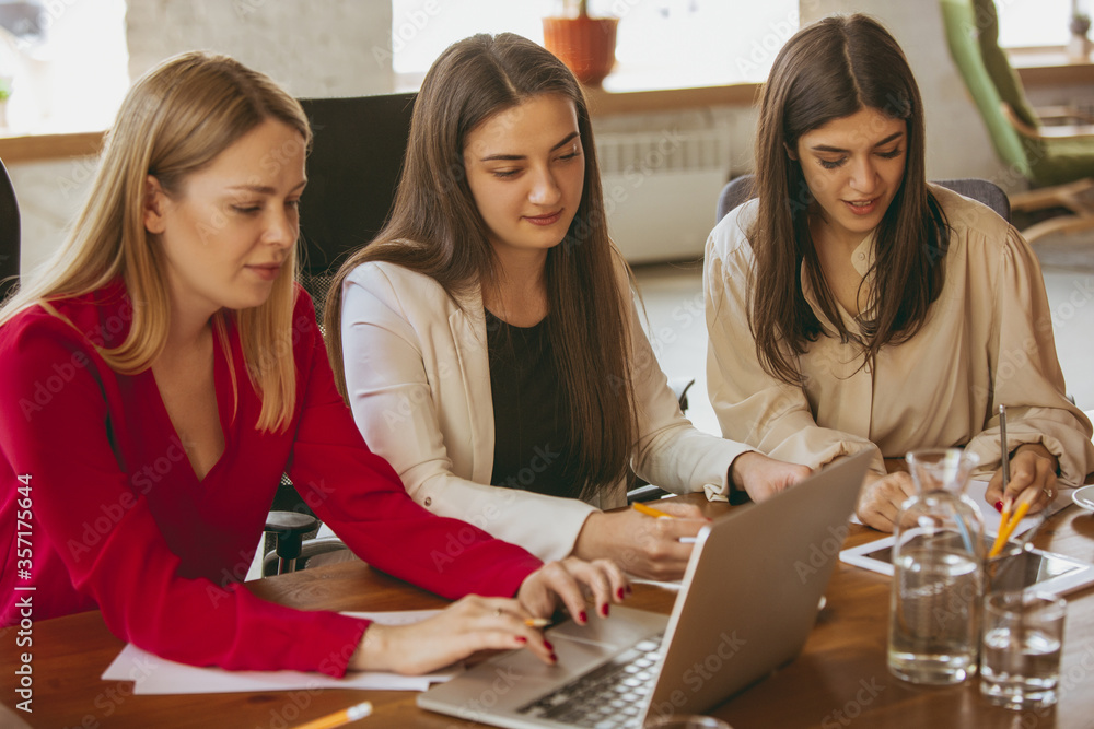 Fototapeta premium Paperwork. Young business woman in modern office with team. Creative meeting, tasks giving. Women in front-office working. Concept of finance, business, girl power, inclusion, diversity, feminism.