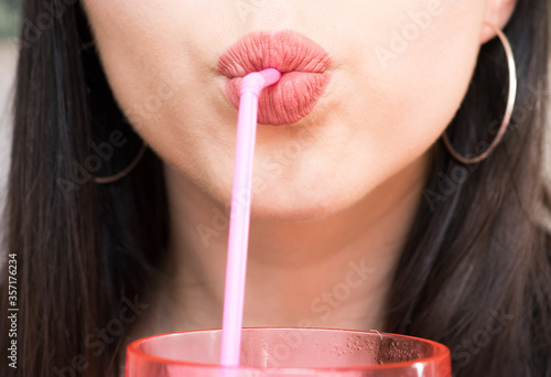 Obraz na plátně Close up of woman's lips drinking with a pink straw