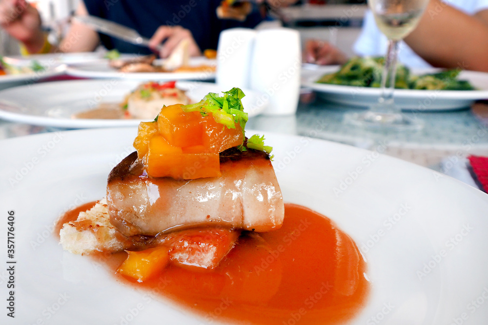 fois gras in mango mixed fruit sauce served on white plate dish in restaurant environment fois gras in mango mixed fruit sauce served on white plate dish in restaurant environment