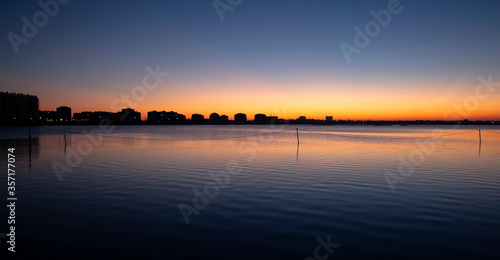 A series of landscapes of a salt lake in a seaside resort after sunset. The magical light that the sun leaves after it disappears. With reflected buildings on the horizon. Pomorie resort, Bulgaria.