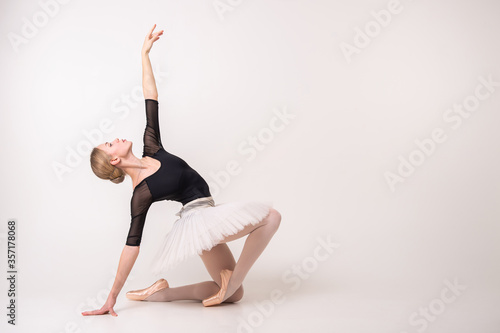 The portrait of beautiful young blonde woman gymnast training calilisthenics exercise on white studio background.