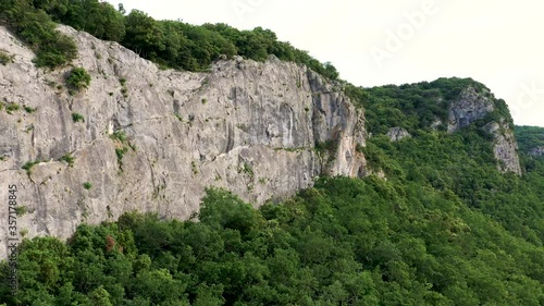 Large aerial dezoom of a huge limestone cliff surrounded by forest