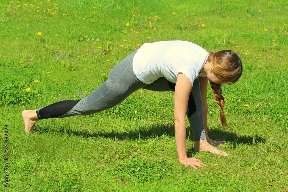 Fototapeta premium Young woman of European appearance does yoga in summer nature