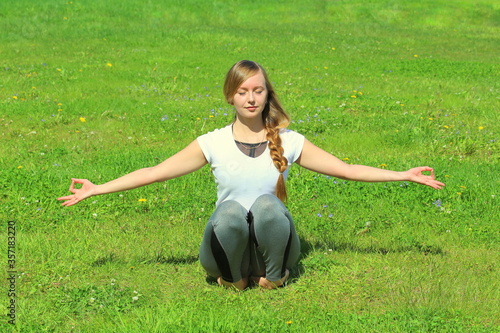 Young woman of European appearance does yoga in summer nature photo