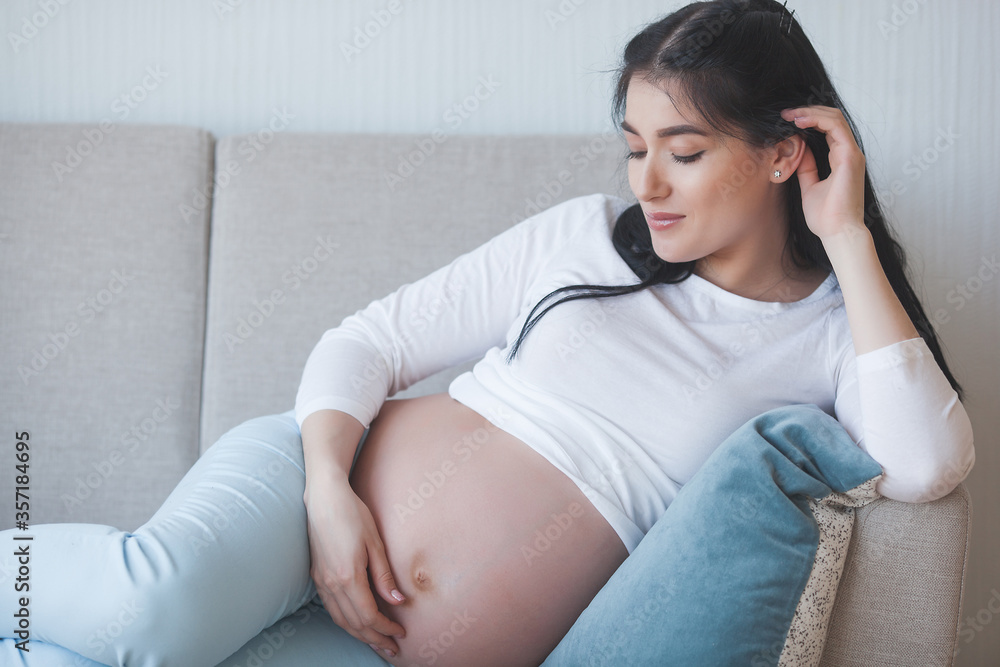 Attractive young woman expecting a child. Pregnant woman. Female indoors embracing her stomach. Attractive young woman expecting a child. Pregnant woman. Female indoors embracing her stomach.