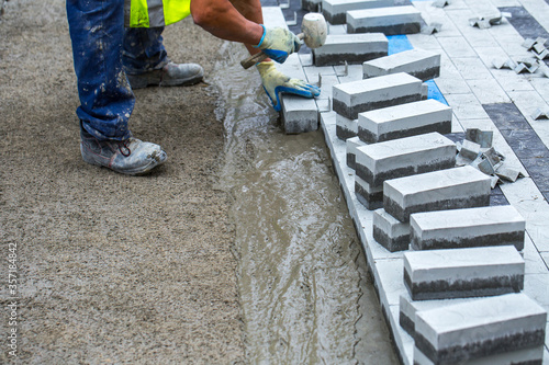 Construction work on pavement. Installation of concrete paver blocks on the sidewalk. The worker pavers pavement bricks on a pre-prepared surface of concrete mortar. photo