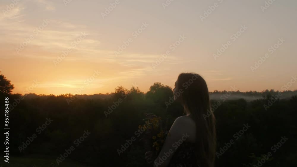 silhouette beautiful girl with bouquet of wildflowers at sunset, young woman with long hair in dress walking on nature,shooting with a crane silhouette beautiful girl with bouquet of wildflowers at sunset, young woman with long hair in dress walking on nature,shooting with a crane