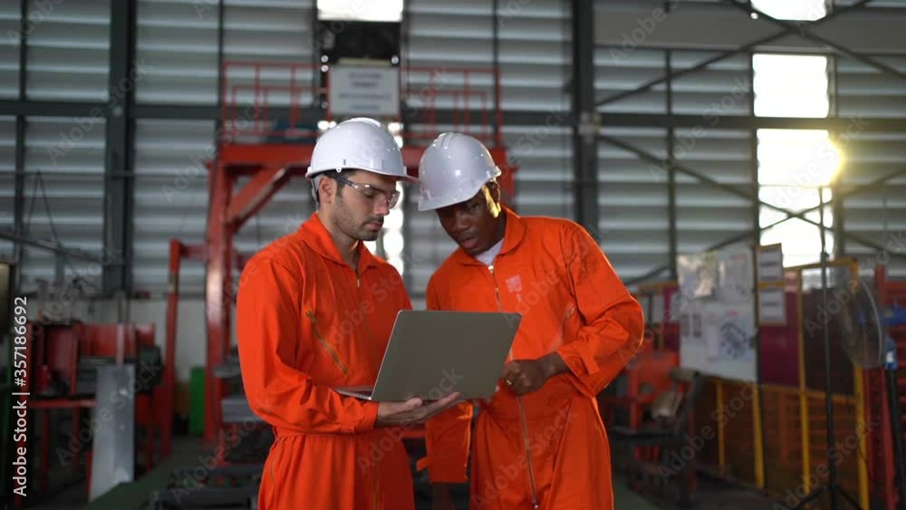 Two workers in production plant as team discussing, industrial scene in background Two workers in production plant as team discussing, industrial scene in background