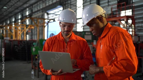Two workers in production plant as team discussing, industrial scene in background
