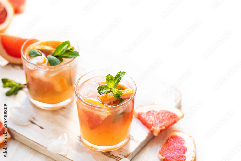 Grapefruit cocktails with mint and ice. Cold summer citrus fresh beverage on light wooden background Grapefruit cocktails with mint and ice. Cold summer citrus fresh beverage on light wooden background