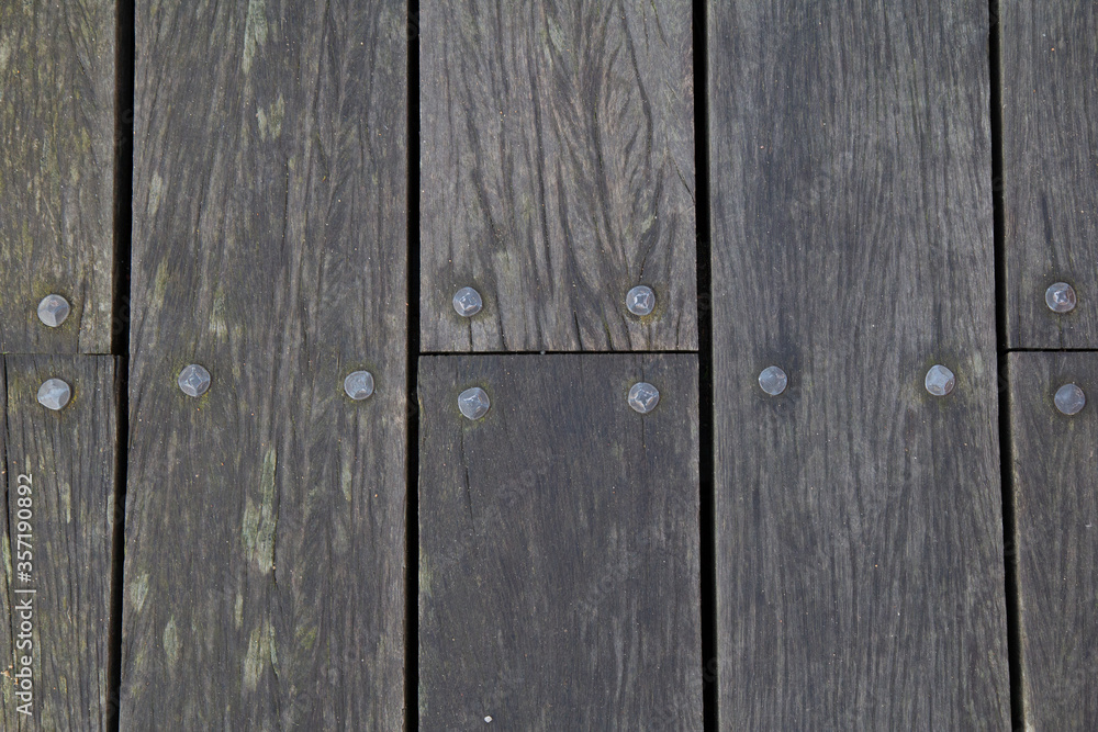 Fototapeta premium Top down view of wooden plank with texture, moss, cracks and nails on an outdoor walkway