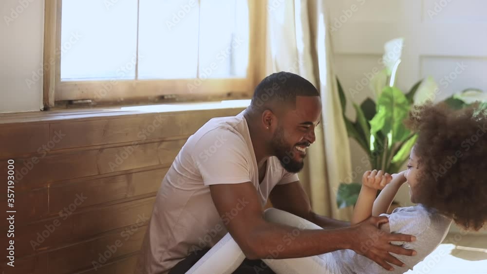 Happy african american family cute small funny child daughter and black father playing laughing tickling together, loving dad and little kid girl hugging cuddling bonding at home on fathers day Happy african american family cute small funny child daughter and black father playing laughing tickling together, loving dad and little kid girl hugging cuddling bonding at home on fathers day