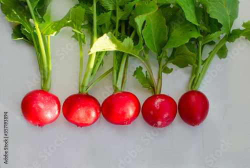 Fresh organic red radishes with green leaves on withe table. Healthy nutrition concept. New crop of vegetables grown in the garden. Harvest 2020. High quality photo