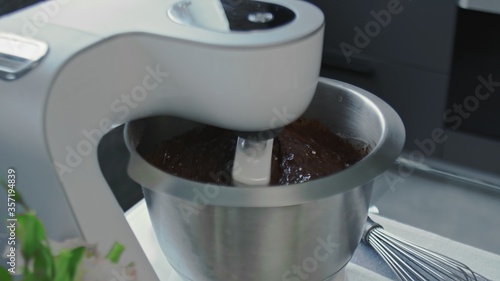 Cooking cake at home. Close up of mixer with chocalate dought for cake photo