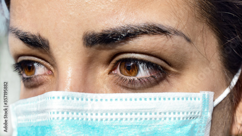 Tired look of a health worker wearing a surgical mask during a break. Overworked healthcare professional