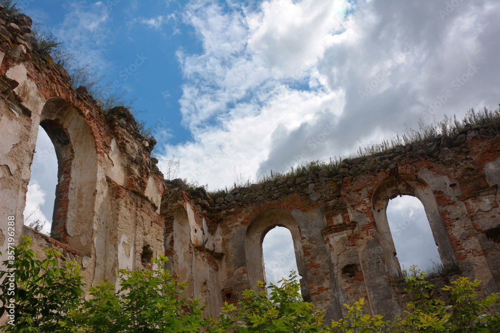 Walls of a ruined ancient estate with windows without glass, instead of a roof a blue sky with white clouds, Ternopil region, Ukraine.