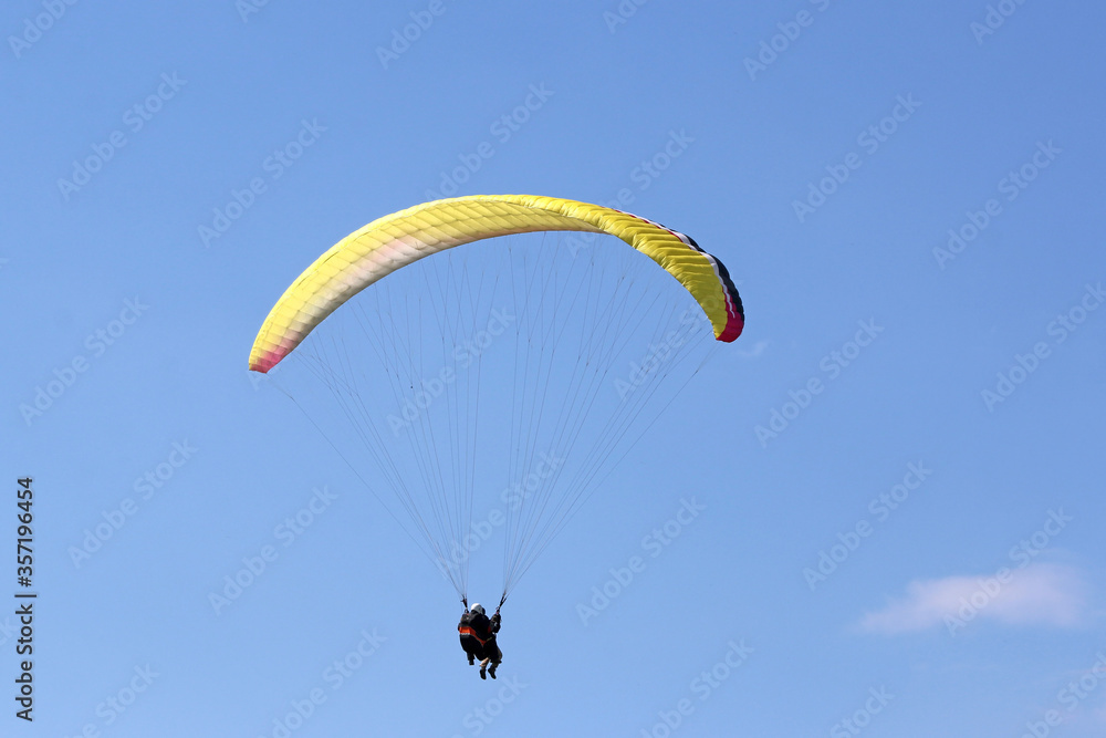 Tandem Paraglider flying wing in a blue sky Tandem Paraglider flying wing in a blue sky