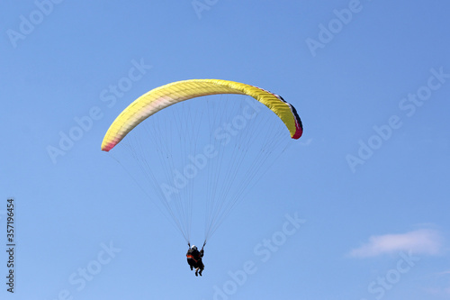Tandem Paraglider flying wing in a blue sky 
