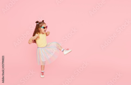 Leinwand Poster Portrait of surprised cute little toddler girl  in sunglasses over pink background