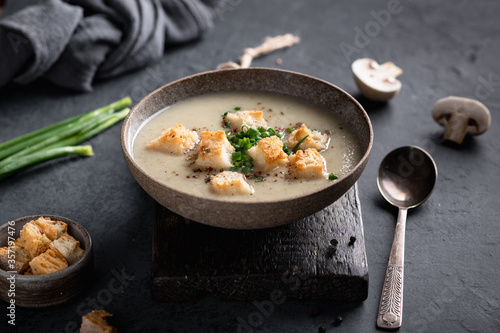 mushroom cream soup with champignons and croutons in a ceramic bowl on a dark background