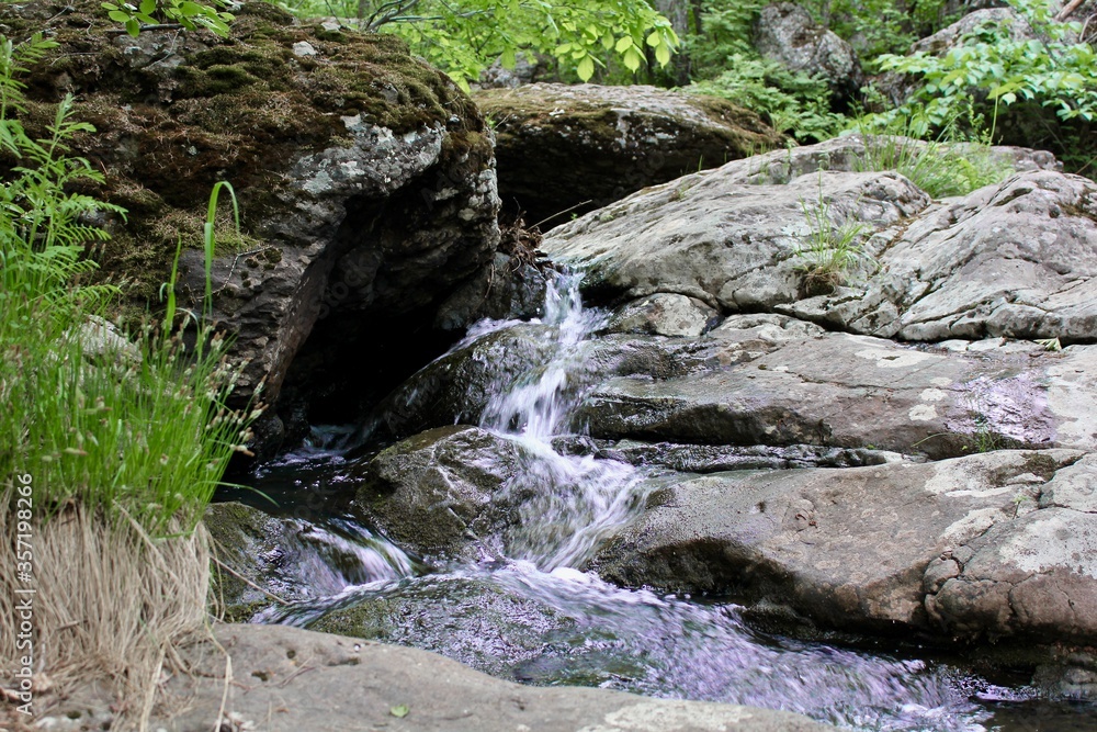 Amazing waterfall in the middle of mountain forest. River full of water during spring, beautiful flowing mass. Lovely contrast of water and surrounding forest green. Stones and fresh green leaves. Amazing waterfall in the middle of mountain forest. River full of water during spring, beautiful flowing mass. Lovely contrast of water and surrounding forest green. Stones and fresh green leaves.
