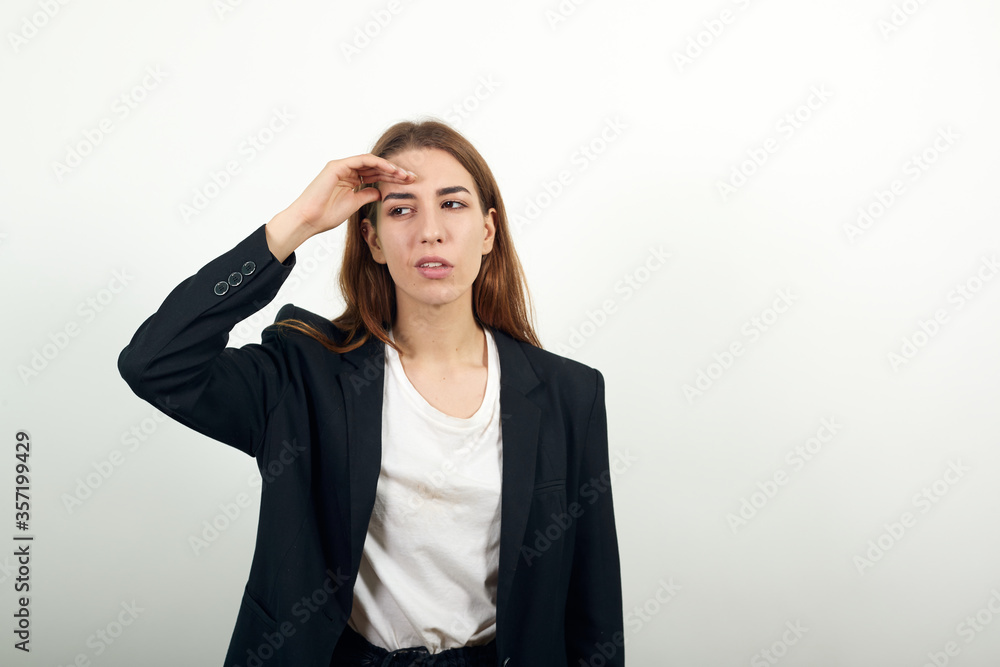 Stress or a headache grimacing in pain holds the back of her neck indicating location. Fatigue during workaholism labor. Young attractive woman with brown hair in light t-shirt and black jacket Stress or a headache grimacing in pain holds the back of her neck indicating location. Fatigue during workaholism labor. Young attractive woman with brown hair in light t-shirt and black jacket
