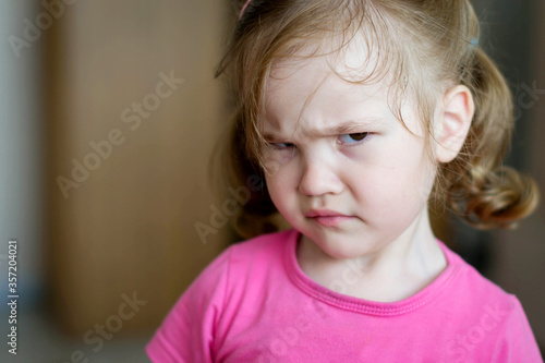 Foto Little three year old girl looks angrily into the frame