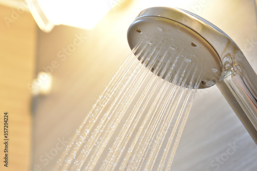 水の出ているシャワーヘッドと照明